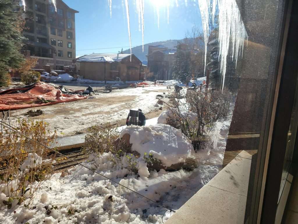 Snowy urban street with ice and sunlight reflection.
