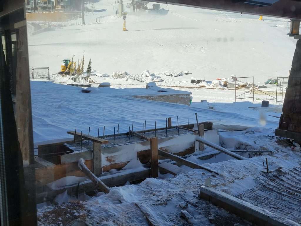 Construction site covered in snow with workers and equipment.