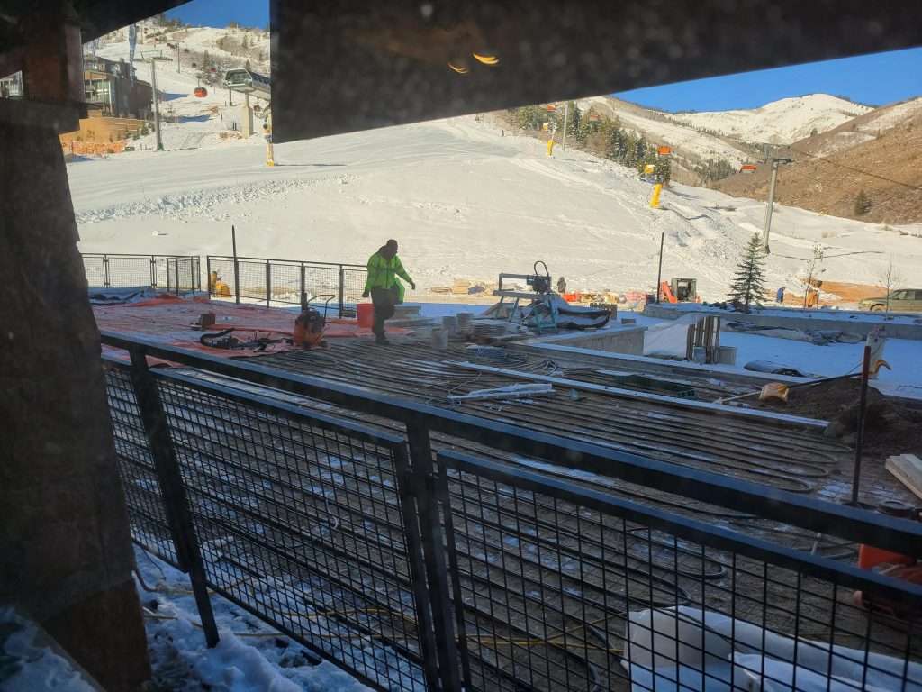 Workers preparing an outdoor stadium with tiered seating under a clear sky.