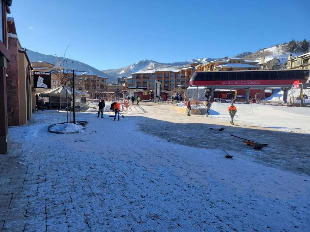 Snow-covered street with people walking in a mountainous town.