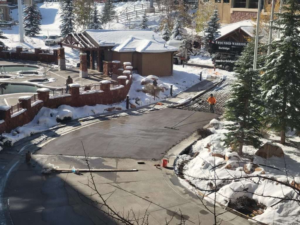 Winter scene with cleared road surrounded by snow and wooden cabins.