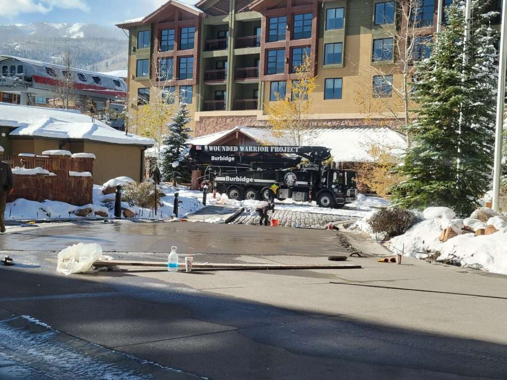 Ski resort entrance with snow and people near a lodge.