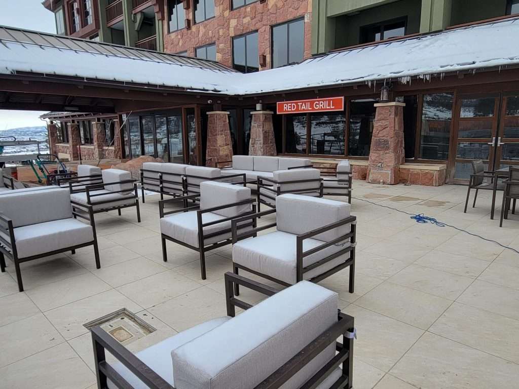 Outdoor seating area with modern cushioned chairs and tables under canopies.