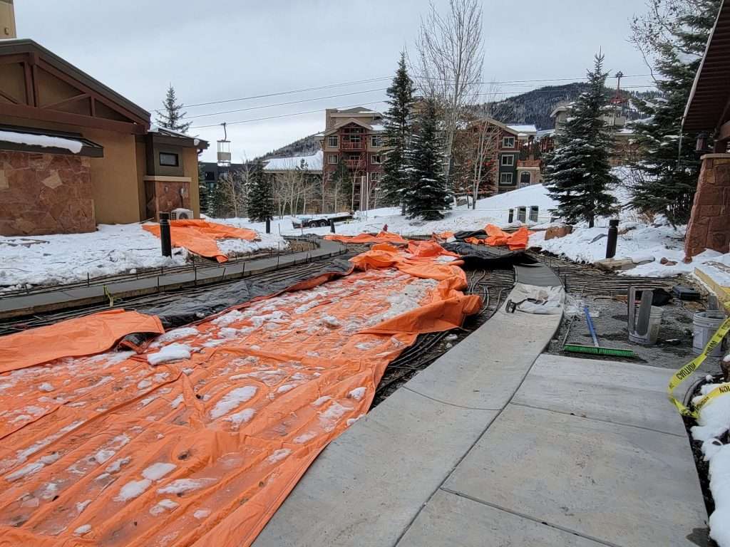 Construction site with orange protective coverings and exposed ground.