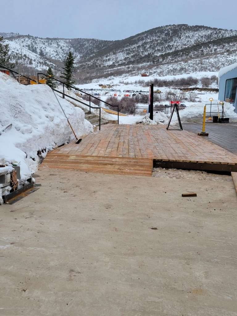 Construction of a wooden deck in a snowy mountain area.